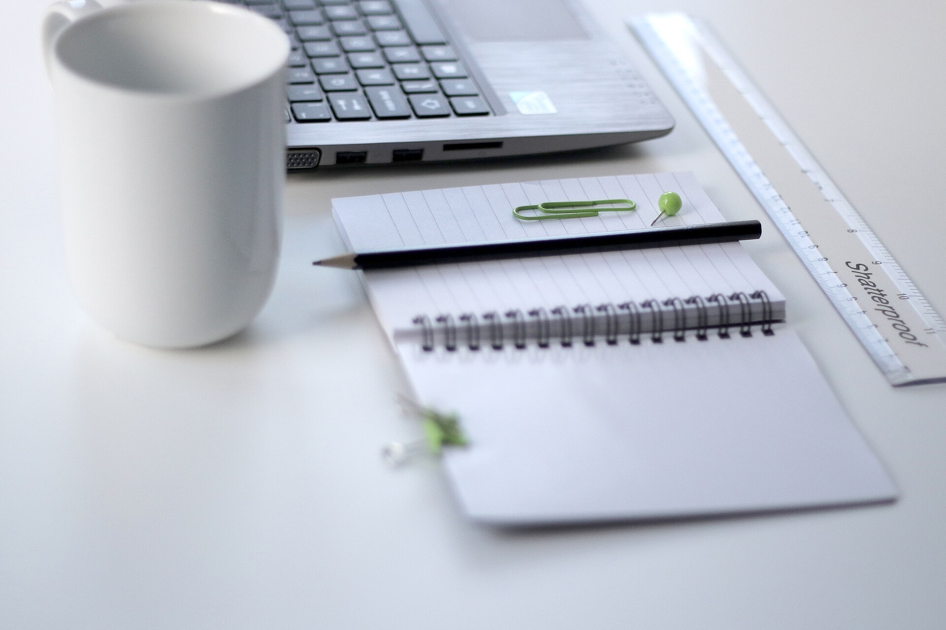 Laptop, notebook and coffee mug on a desk, used to research whether AsianDating.com is legit