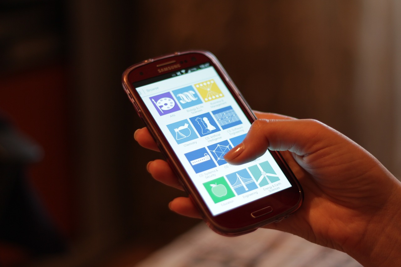 Hands holding a smartphone with app icons, checking whether AsianDating.com is legit before signing up